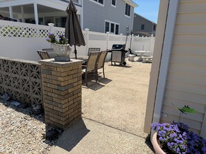 A patio area with a grill, outdoor furniture, and a potted plant. - Beautiful 3-bedroom bay side house with AC in charming Lavallette (Lavallette)