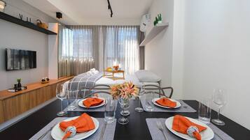 Un comedor moderno con una mesa negra, platos blancos y servilletas naranja.