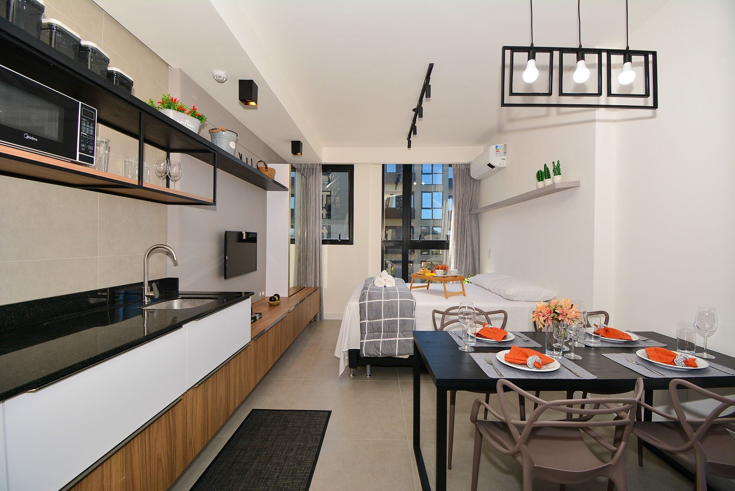 A modern kitchen with a built-in microwave, a dining area with a table set for four, and a view through a window.