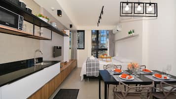 A modern kitchen with a built-in microwave, a dining area with a table set for four, and a view through a window.