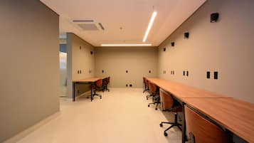 A conference room with long tables and chairs, a tiled floor, and recessed lighting.