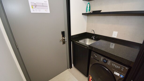 A compact kitchen with a built-in washing machine, a sink, and a small countertop. - Studio em frente a UFSC e HU - 625A (Florianópolis)