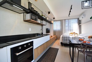 A modern kitchen with a built-in oven, microwave, and black countertop. - Studio em frente a UFSC e HU - 625A (Florianópolis)
