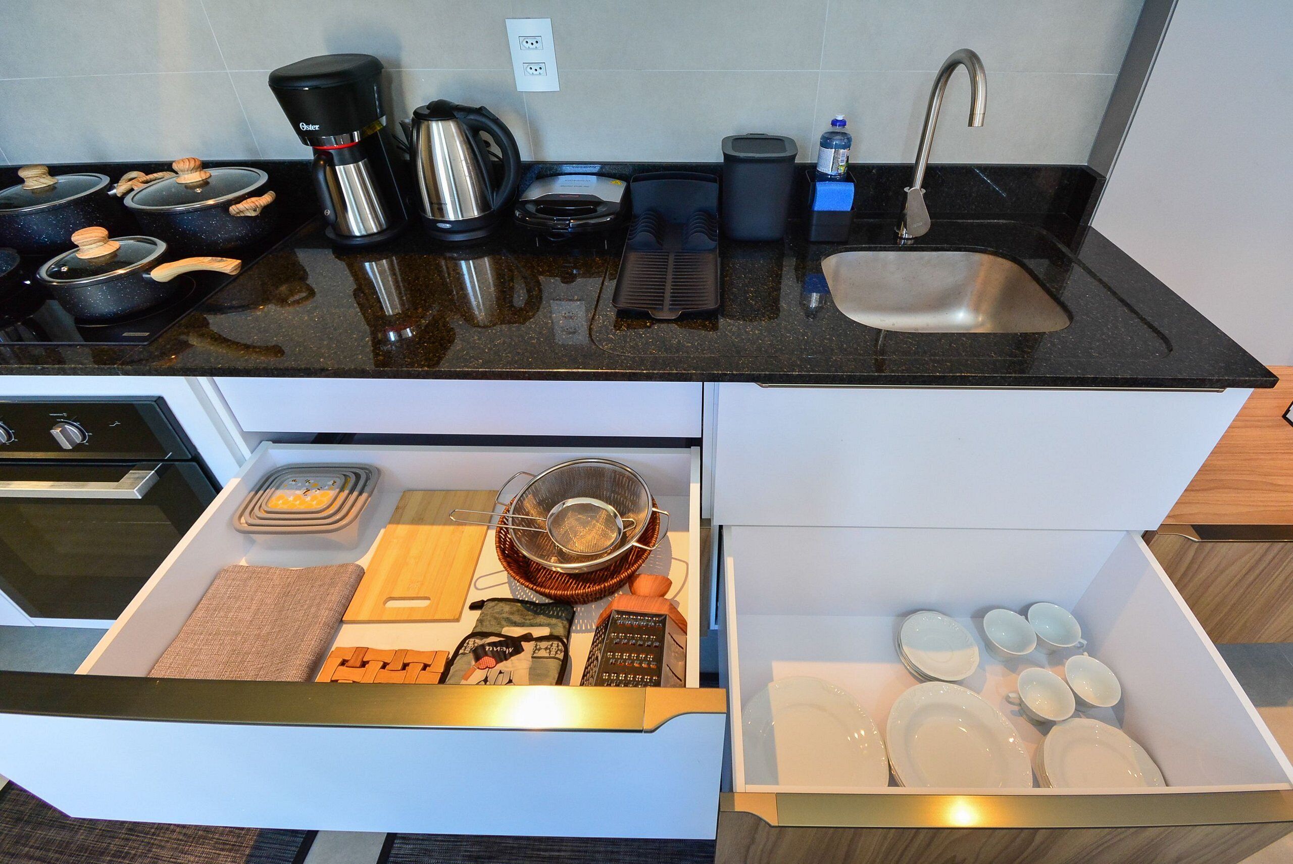 Una cocina equipada con estufa, cafetera, hervidor y pileta.