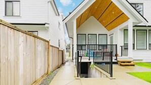 A residential property with a covered porch, a wooden fence, and a paved walkway. - Bright 2BR Suite Near White Rock & Vancouver (Surrey)