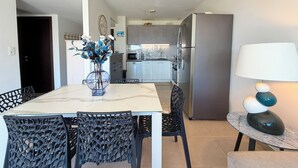 A modern kitchen with stainless steel appliances, a dining table with chairs, and a vase with flowers. - T2 Porticcio sea view beach on foot (Grosseto-Prugna)