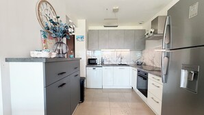 A modern kitchen with grey cabinets, a stainless steel refrigerator, a microwave, and a dishwasher. - T2 Porticcio sea view beach on foot (Grosseto-Prugna)