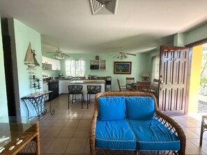 A kitchen with a dining area, a sofa, and a door leading outside. - Beautiful Caribbean Beach Bungalow in Palma Real Resort, Honduras (La Ceiba)