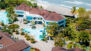 Ein Resort mit großem Pool, Blick auf den Strand und tropischer Bepflanzung.