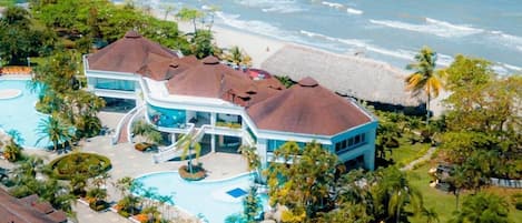 Ein Resort mit großem Pool, Blick auf den Strand und tropischer Bepflanzung.
