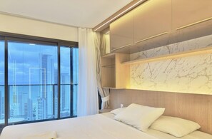 A modern hotel room with a large bed, a marble accent wall, and a city view. - Beach Class Meireles (Fortaleza)