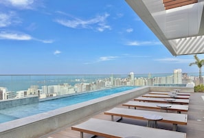 A rooftop pool with a city view, outdoor seating, and a glass railing. - Beach Class Meireles (Fortaleza)