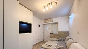 A small, modern bedroom with a bed, a TV, and a window with blinds. - Capo & Nemo Apartments Vodice - Classic One Bedroom Apartment (Vodice)