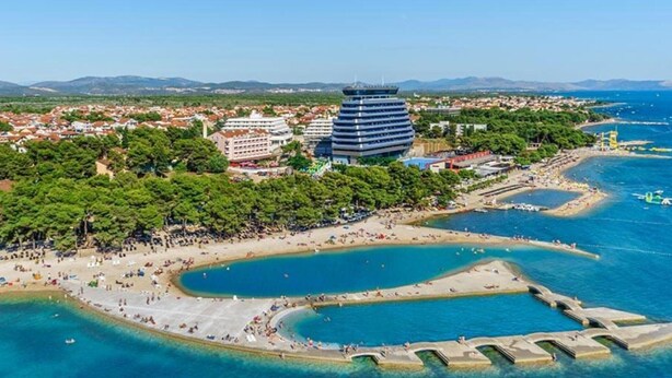 An aerial view of a coastal area with a large hotel, a beach, and a marina. - Capo & Nemo Apartments Vodice - Classic One Bedroom Apartment (Vodice)