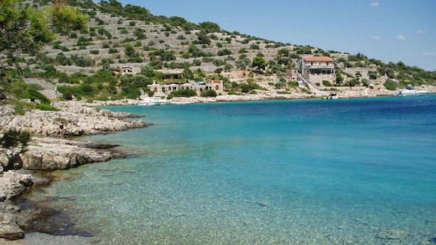 A coastal area with clear waters, rocky shorelines, and buildings on a hillside. - Apartments Mediterraneo Blues - Two bedroom apartment with sea view (Rustico) (Kaprije)