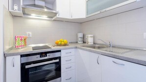 Una cocina moderna con gabinetes blancos, horno empotrado, fregadero y cafetera.