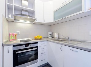 Eine moderne Küche mit weißen Schränken, einem Backofen, einer Spüle und einer Kaffeemaschine.