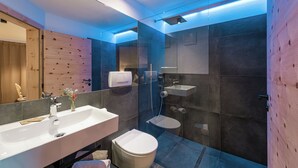 Et moderne badeværelse med stor vask, toilet og bruseområde.