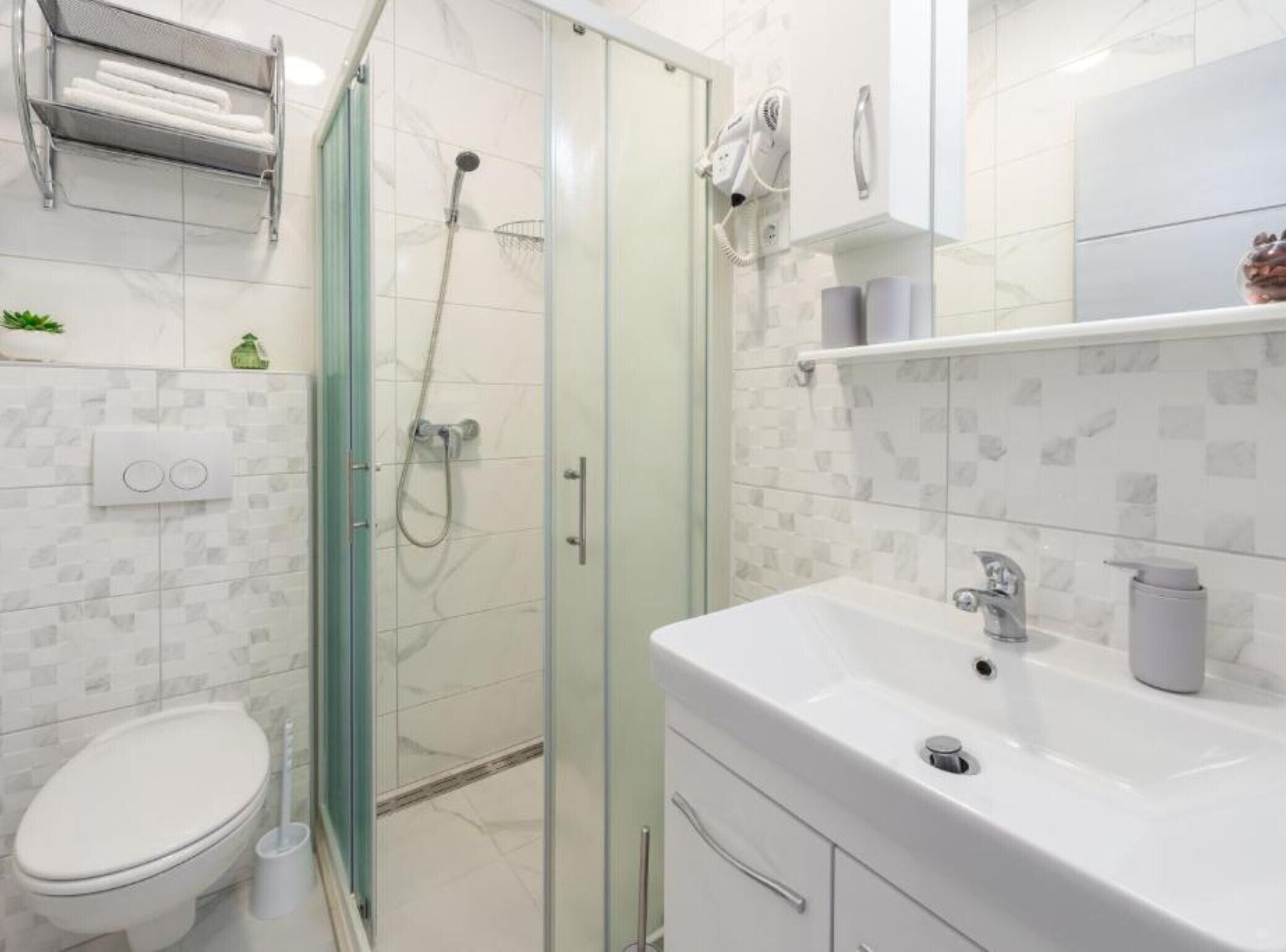 Une salle de bain moderne avec une douche à parois de verre, un lavabo blanc et des toilettes.