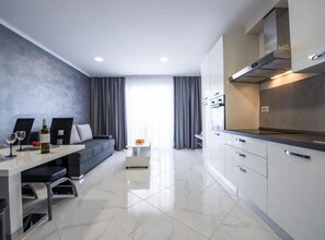Una cucina moderna con mobili bianchi, forno integrato e cappa aspirante in acciaio inossidabile.