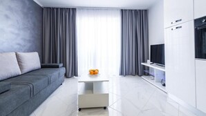 Een moderne woonkamer met een grijze bank, een witte salontafel en een televisie op een kast.