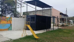 A playground with a yellow slide and a mural on the wall. - Container Black  (Rio de Janeiro)