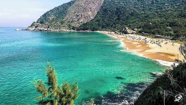 A coastal beach with clear turquoise waters, a sandy shore, and a mountainous backdrop. - Container Black  (Rio de Janeiro)