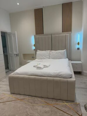 Ein modernes Schlafzimmer mit einem großen Bett, Nachttischen und einem Kleiderschrank.