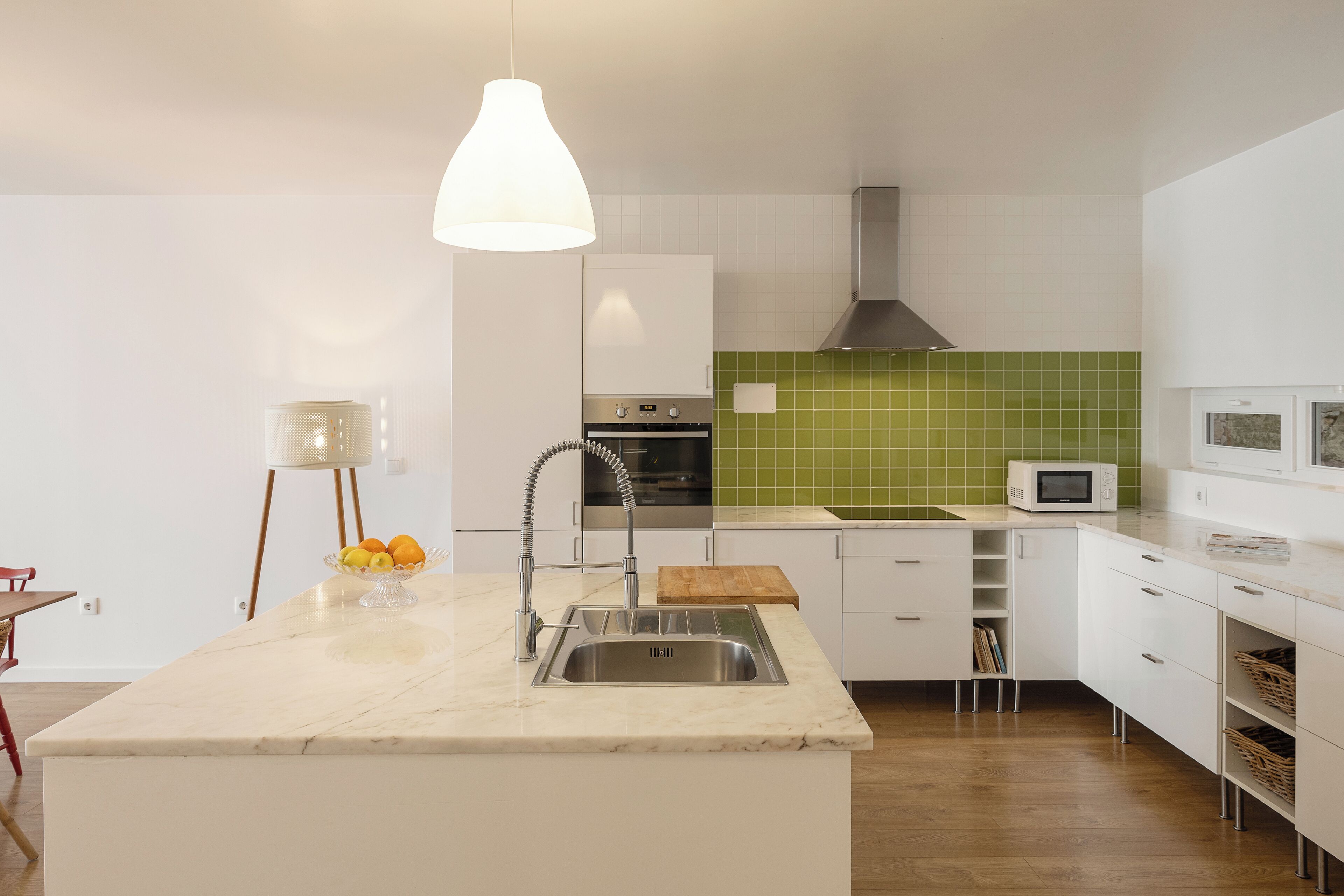 A modern kitchen with a central island, stainless steel sink, and a microwave.