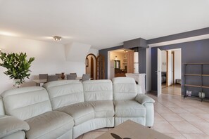 Ein modernes Wohnzimmer mit einem Ecksofa, einem Essbereich und einer Küche im Hintergrund.