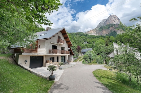 A two-story house with a balcony, a garage, and a driveway leading to a mountain.. Duplex La Source Amélie Apartment: Mountain View, Private Terrace, Wi-Fi