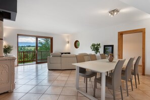 A spacious living area with a balcony, a dining table with chairs, and a sofa.