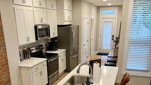 Una cocina moderna con armarios blancos, electrodomésticos de acero inoxidable y una isla central con un lavamanos.