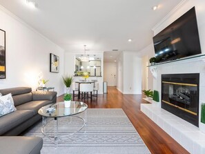 A modern living room with a sofa, coffee table, fireplace, and a TV mounted on the wall. - Modern Elegance ~ Excellent Location ~ Steps to the Beach! (Saint Augustine)