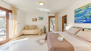 A bedroom with a bed, a bedside table, a window with curtains, and a painting on the wall. - Nice stone house with sea view & outdoor whirlpool (Patù)