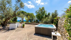A hot tub, outdoor seating, and a view of the sea. - Nice stone house with sea view & outdoor whirlpool (Patù)