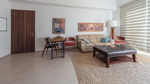Ein Wohnzimmer mit einer Couch, zwei Sesseln, einem Couchtisch, einem Teppich und Kunstwerken an der Wand.