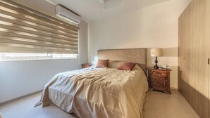 Ein Schlafzimmer mit Bett, Nachttisch, Lampe und Kleiderschrank.