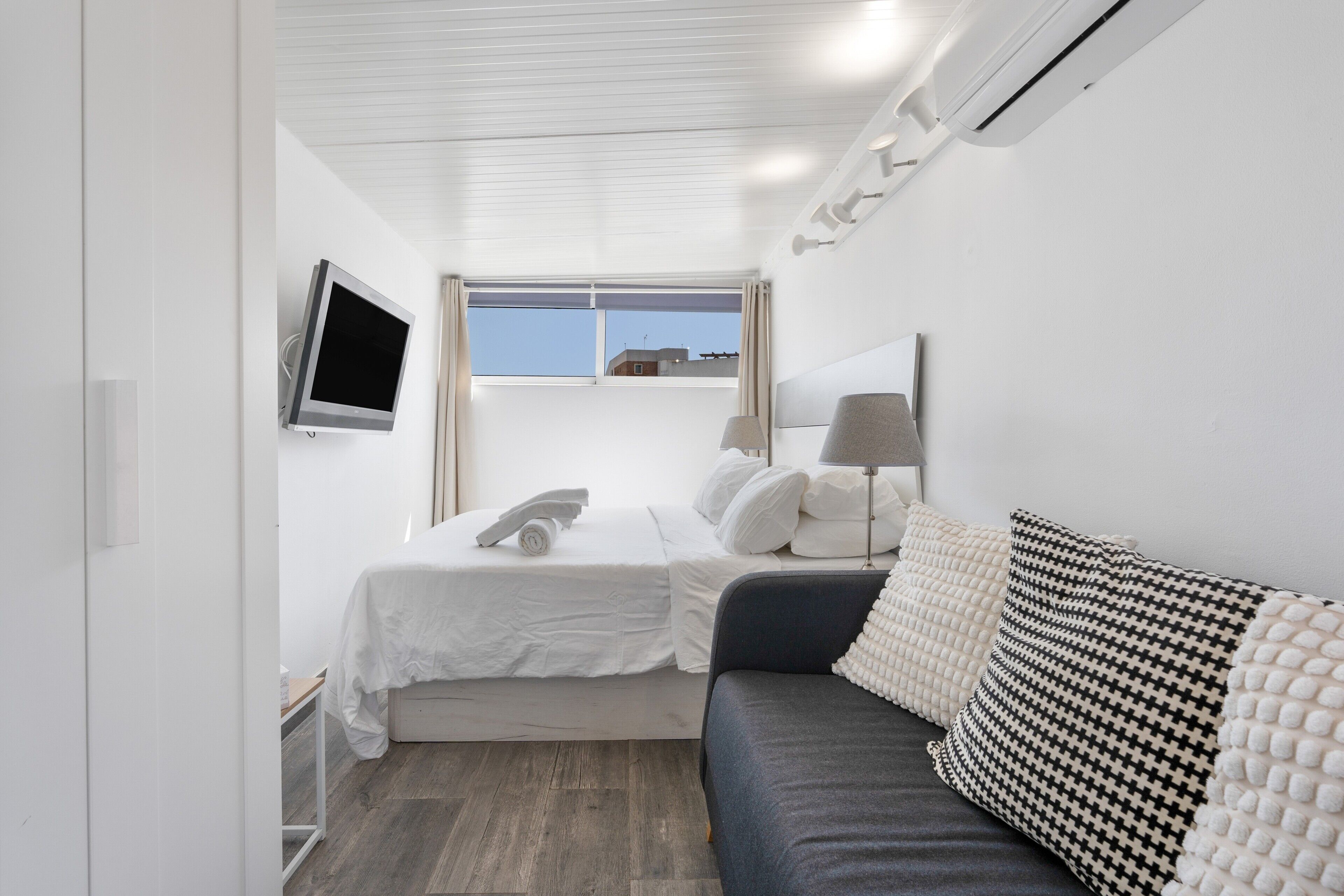 Ein Hotelzimmer mit Bett, Sofa, Fernseher, Fenster und Klimaanlage.