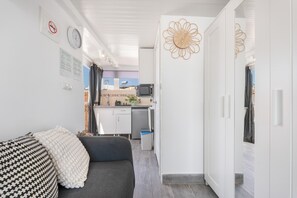 Ein kompakter Wohnraum mit Sofa, Küchenzeile, Essbereich und Kleiderschrank.