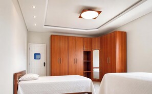 Ein Schlafzimmer mit einem Bett, zwei Nachttischen, einem Kleiderschrank und einer Deckenleuchte.