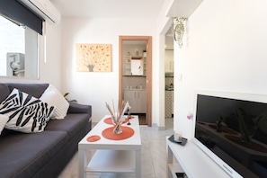 A modern living room with a sofa, a coffee table, a flat-screen TV, and a kitchen in the background. - Apartment 'Casa Jose 2' with Air Conditioning (Torremolinos)
