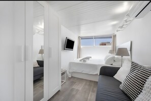 A modern, white-themed bedroom with a bed, a TV, and a window. - Apartment 'Casa Jose 2' with Air Conditioning (Torremolinos)