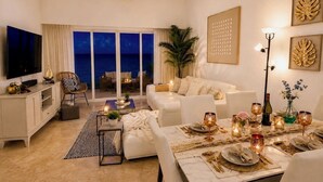 A modern living room with a sofa, dining table set for a meal, and a TV. - OCEANFRONT Punta Palmera Paradise ~ 2 BR apt. in Cap Cana w/Private Beach Access (Punta Cana)