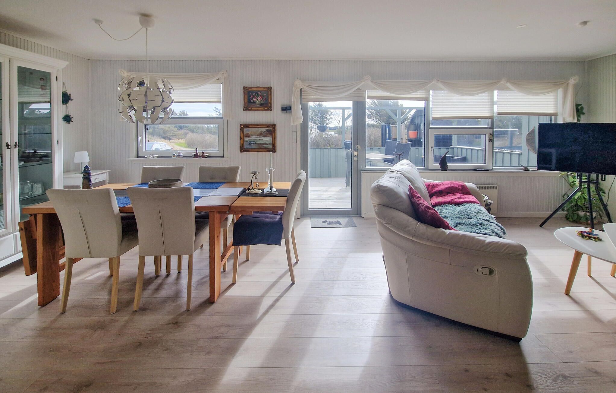 A spacious living area with a dining table, chairs, a sofa, and a television.