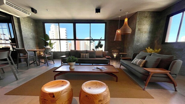 A modern living room with a sofa, coffee table, and two wooden stools. - Condominio Jsmart, Localizacao Ideal (Fortaleza)