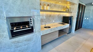 A modern kitchen with a built-in oven, a sink, and a marble backsplash. - Condominio Jsmart, Localizacao Ideal (Fortaleza)