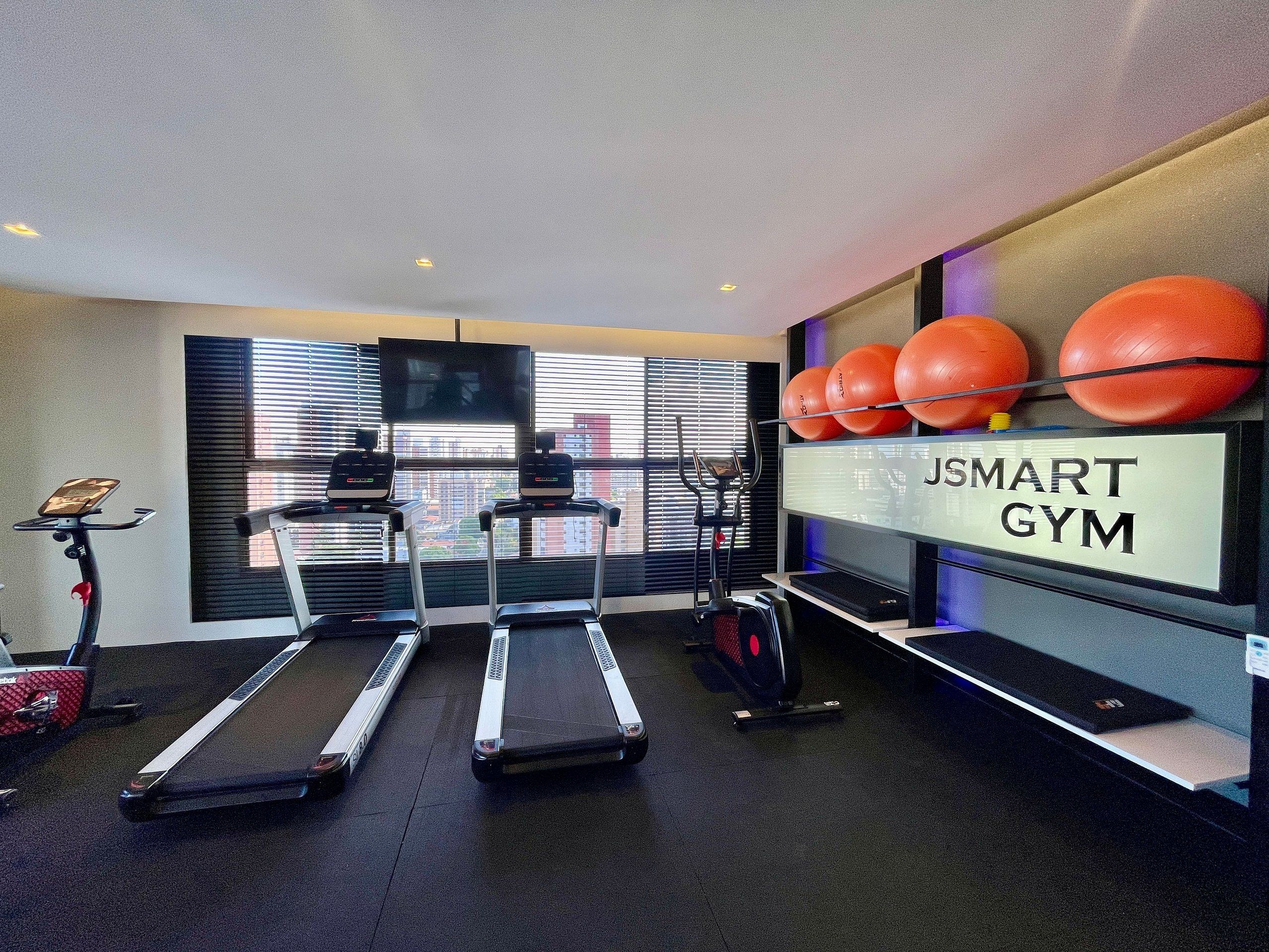 Een fitnessruimte met loopbanden, fitnessballen en een televisiescherm.