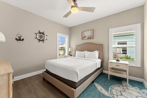 A bedroom with a bed, a nightstand, a ceiling fan, and a window with blinds. - Beach House - Ocean Breeze Cottage (Port St. Joe)