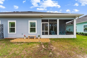 A house with a covered porch, a small garden area with a bench, and a window with shutters. - Beach House - Ocean Breeze Cottage (Port St. Joe)